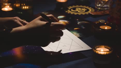 close up of woman drawing astrology lagna or birth chart on candlelit table 2