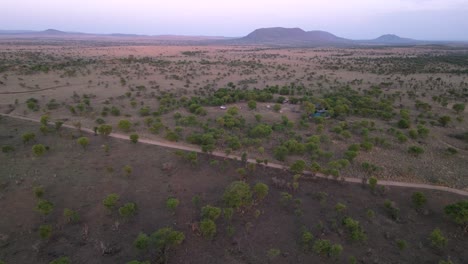 paisaje serengeti africano con camino de tierra y campamento, cierre aéreo en tiro