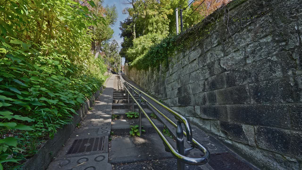A low-angle view of the steep Munatsuki-zaka stone staircase flanked by greenery and stone walls