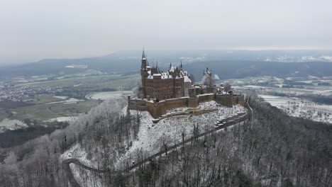 aerial flying towards medieval castle hohenzollern on a mountain on a snowy day during winter in swabia, germany