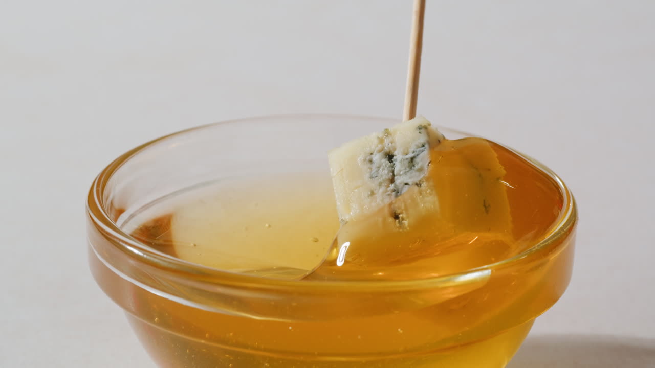 Tasty blue cheese with rosemary, honey and walnuts on white table, close up of Dorblu in cafe pouring in honey.