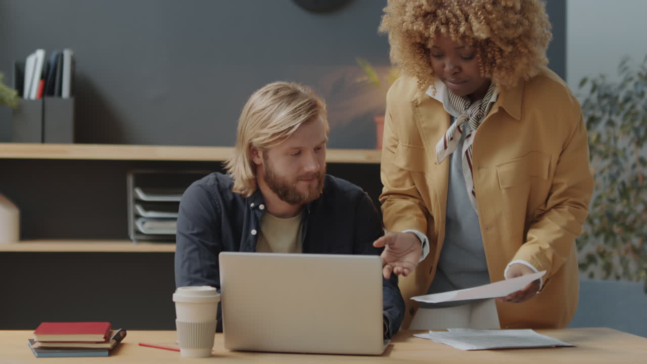 Multiethnic Coworkers Using Laptop and Talking in Office