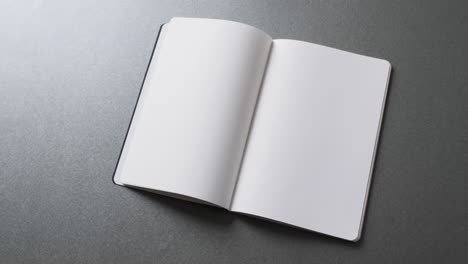 Close-up-of-open-blank-book-with-copy-space-on-gray-background-in-slow-motion