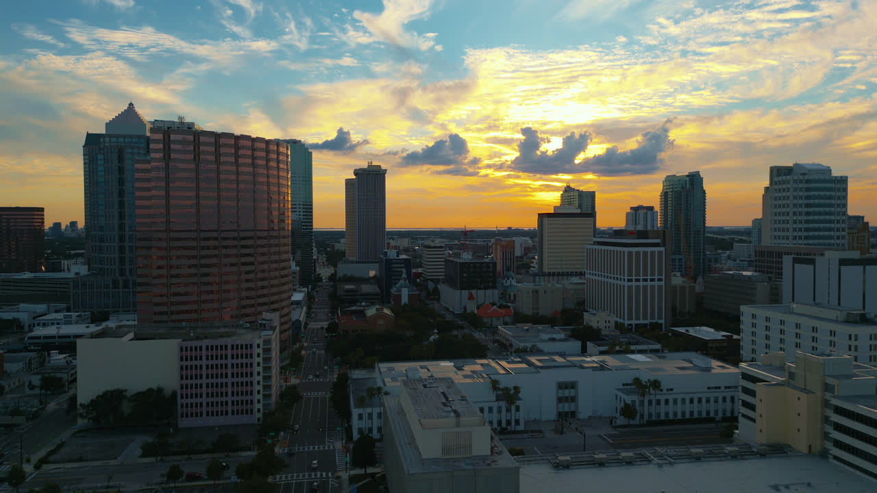 Tampa skyline as the sun begins to set with the buildings glowing in the light, static aerial shot