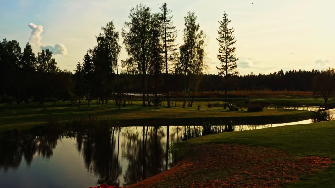 Ostacolo d'acqua di un campo da golf che riflette il cielo al tramonto con un pedalò rosso