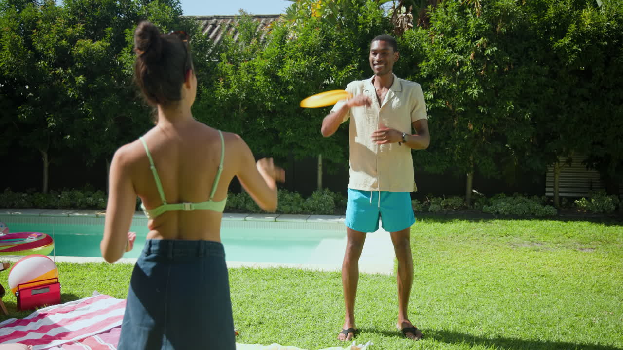 Diverse friends playing frisbee by pool, enjoying sunny day and outdoor fun