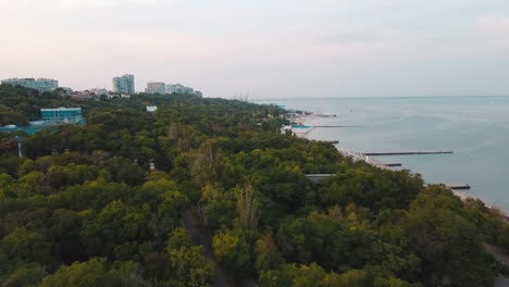 Drone-flying-over-the-trees-next-by-the-sea-shore-in-Odessa,-Ukraine