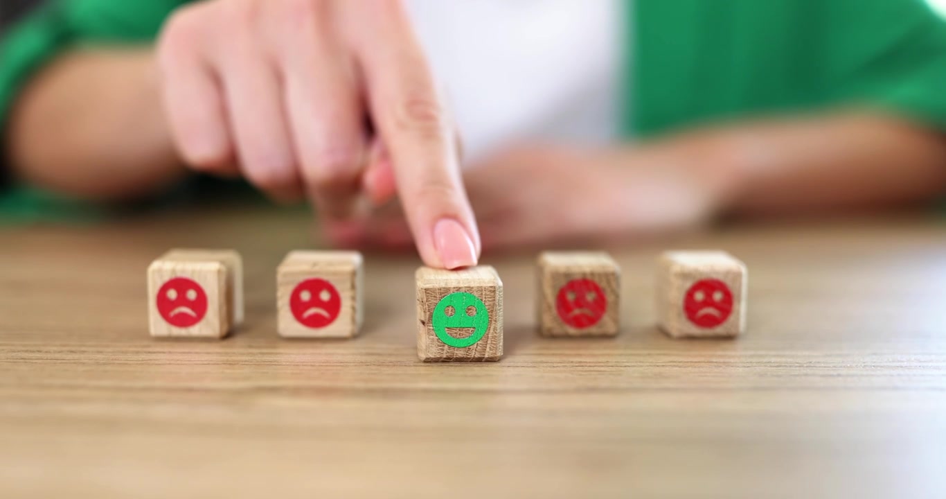Mujer presiona un bloque de madera con una cara sonriente verde sobre la mesa