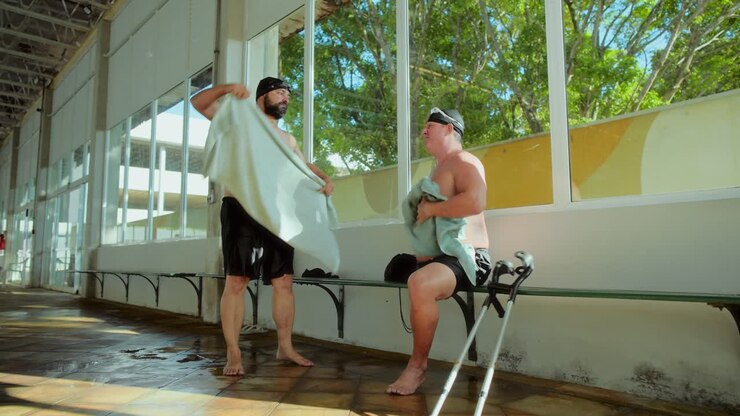 Two Men Drying Themselves After Swimming at an Indoor Pool
