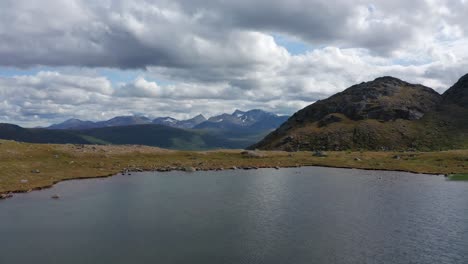 Drone-shot-of-northern-Norway-landscape-with-mountains,-lakes-and-fjord-and-dramatic-sky