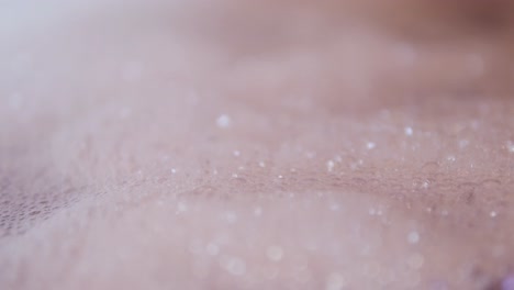 close up view of foam and soapy bubbles on a moving water surface, self care, bathtub, pink background