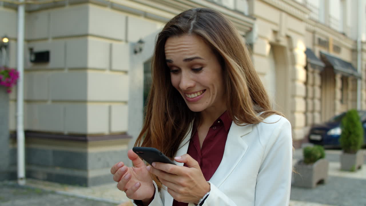 Donna d'affari sorpresa che usa il cellulare all'aperto. Donna d'affari entusiasta.