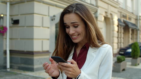 Surprised-businesswoman-using-mobile-phone-outdoors.-Excited-business-woman