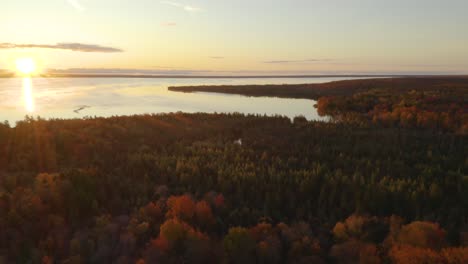 aerial, slow turn to reveal sunset over lake next to autumn forest