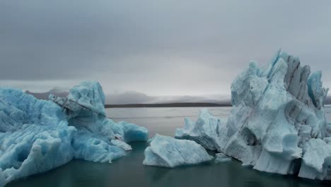 cinematic fly-through between 2 massive icebergs in iceland on a cloudy day