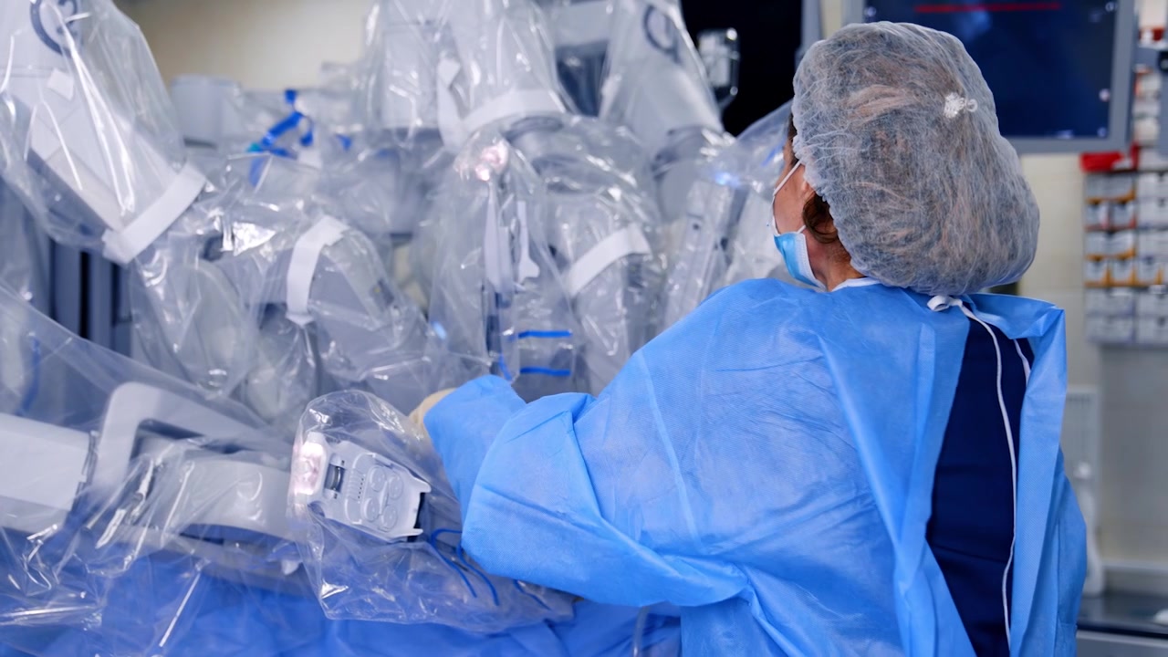 Una dottoressa controlla l'attrezzatura robotica tecnologica coperta di plastica. Sistema chirurgico Da Vinci futuristico in una moderna sala operatoria