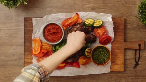 persona del cultivo adornando carne y verduras horneadas