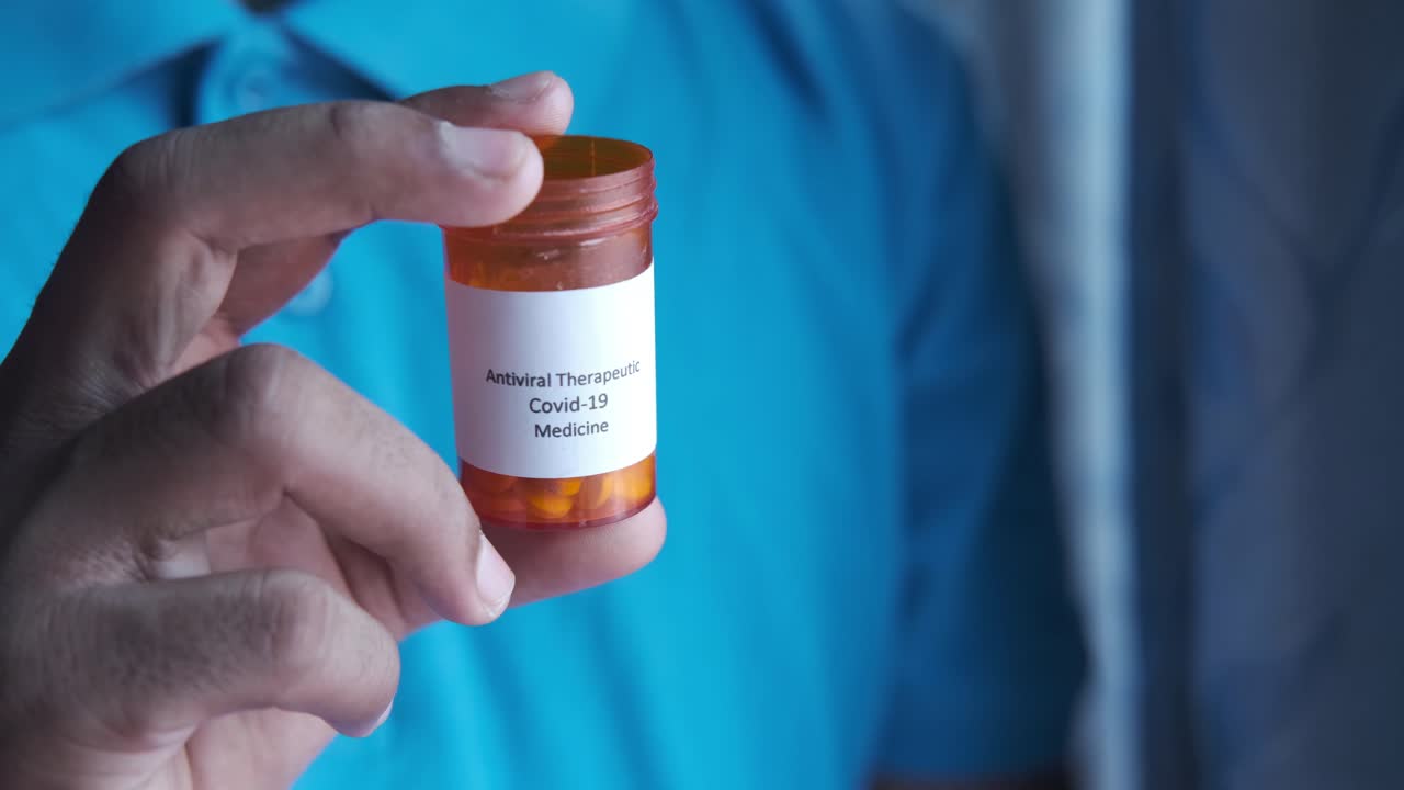 persona que sostiene una botella de medicamento antiviral para la covid-19