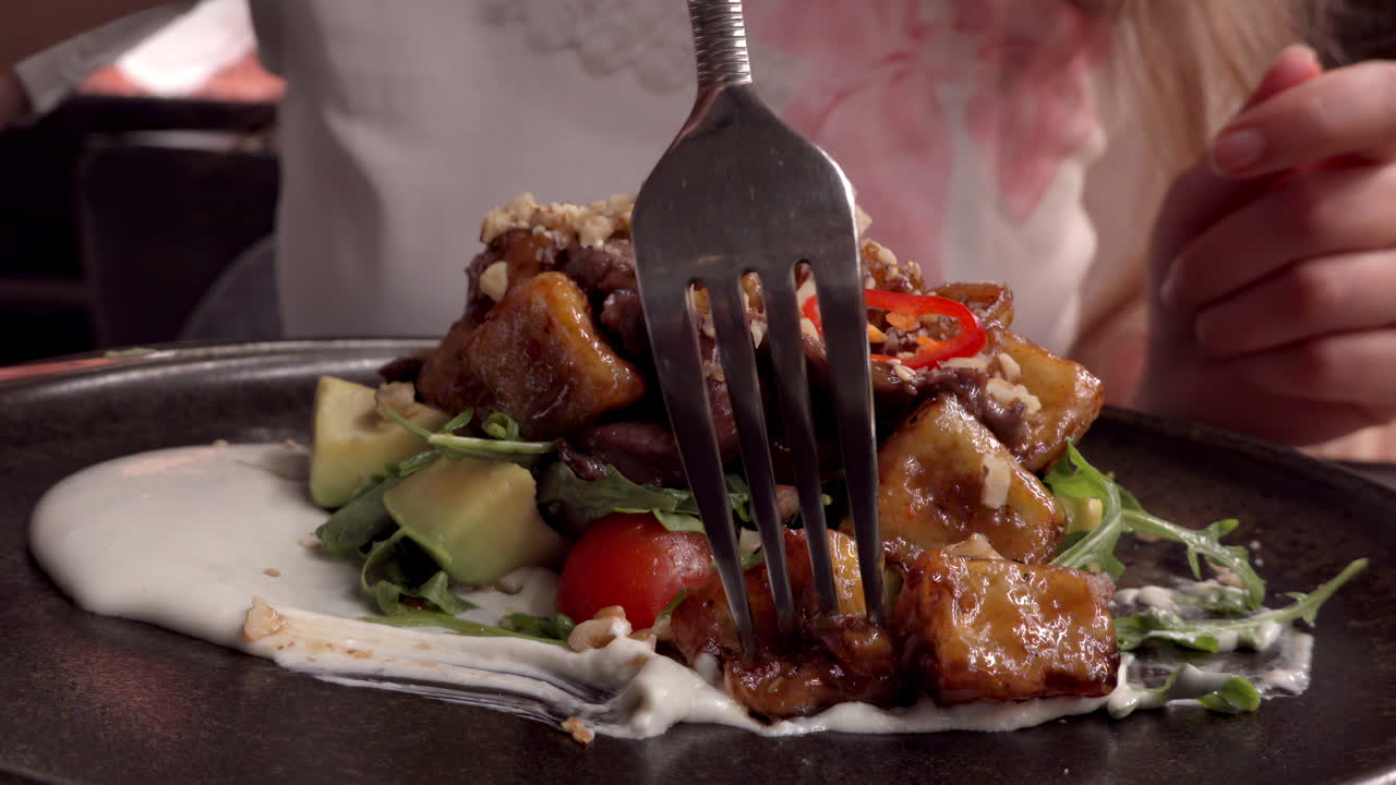 Woman eating a hot salad with veal at a restaurant