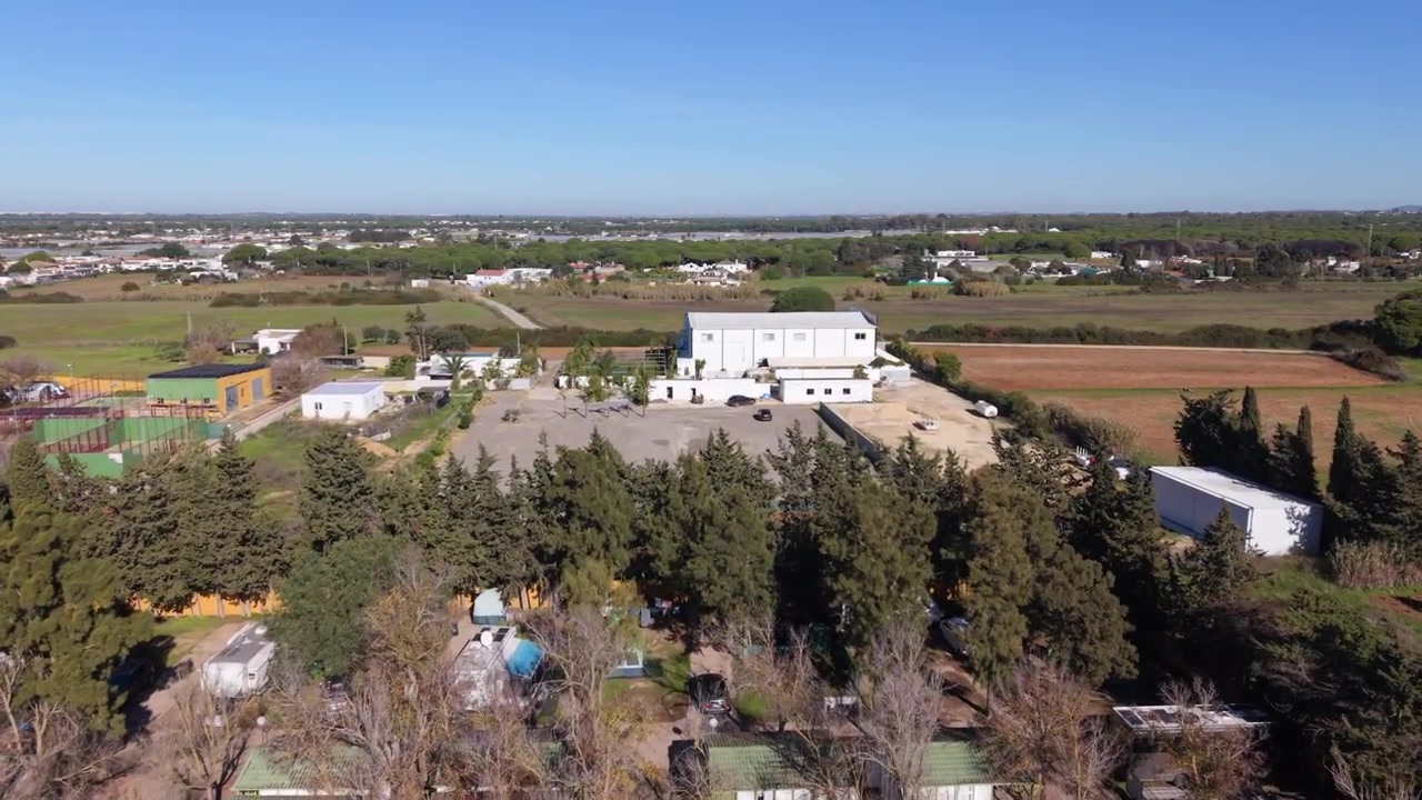 Camping and Bungalows Roche Conil de la Frontera Spain.Forward drone footage over chalets and bungalows towards fields beyond in bright sunlight