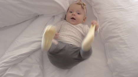 Pretty-blue-eyed-baby-girl-with-bow-on-bed