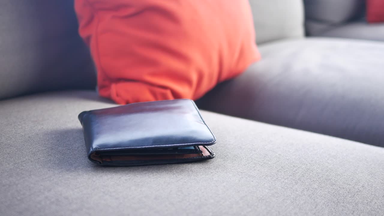 Schwarze Geldbörse auf einem Sofa mit roten Kissen