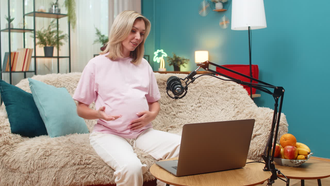 Pregnant woman sharing tips on laptop studio microphone video call laughing giving advice moms care