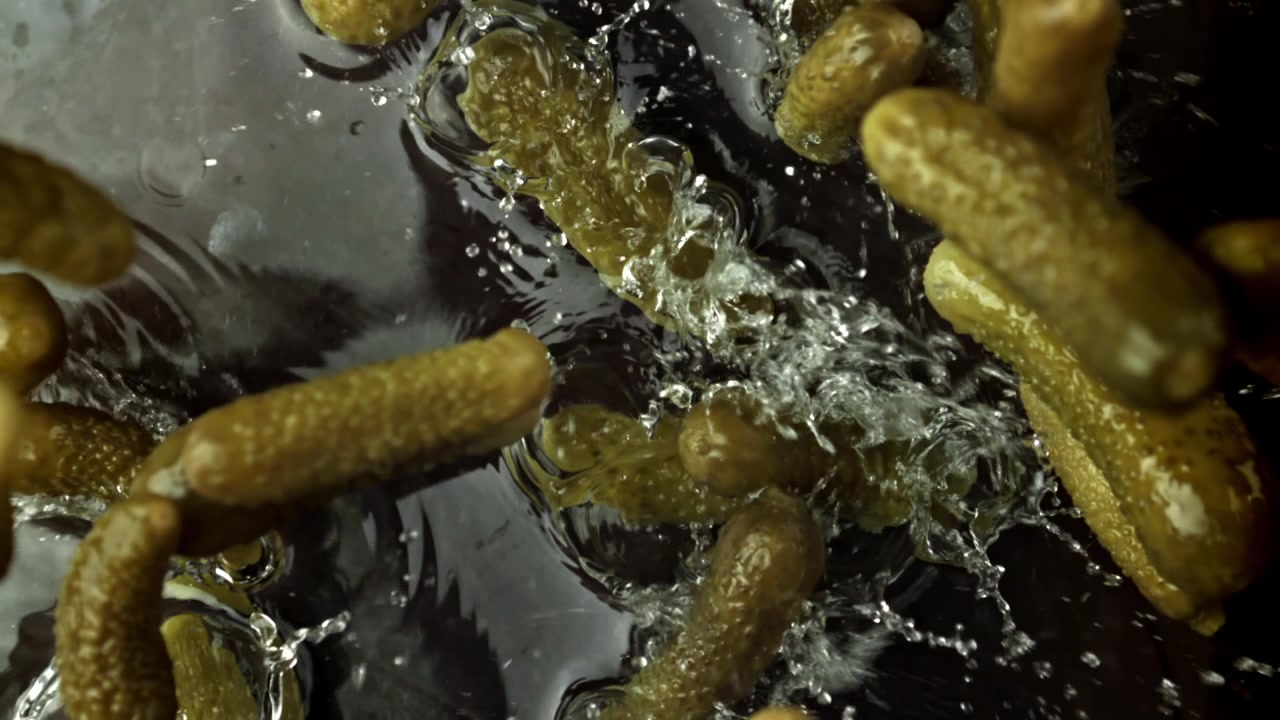 Cornichons frais tombant dans l'eau au super ralenti