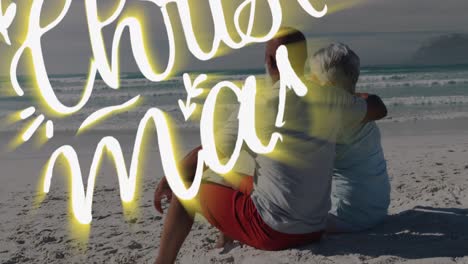 Animation-of-merry-christmas-and-new-year-text-over-happy-diverse-senior-couple-embracing-on-beach