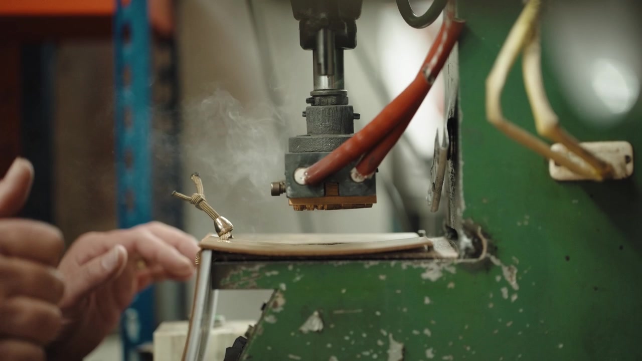 Alimentazione della pelle sotto una testa di pressa per goffratura riscaldata in un'officina di fabbrica