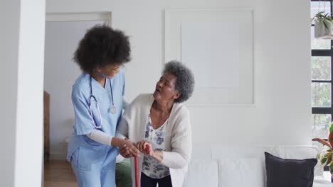 Caring-african-american-female-doctor-helping-senior-african-american-female