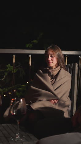 couple looks at burning candles on terrace. woman shares moments with man over glasses of wine at glamping cottage in evening time. memorable atmosphere