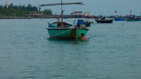 static shot of a fisherman attempting to fix his boat in the ocean at da nang