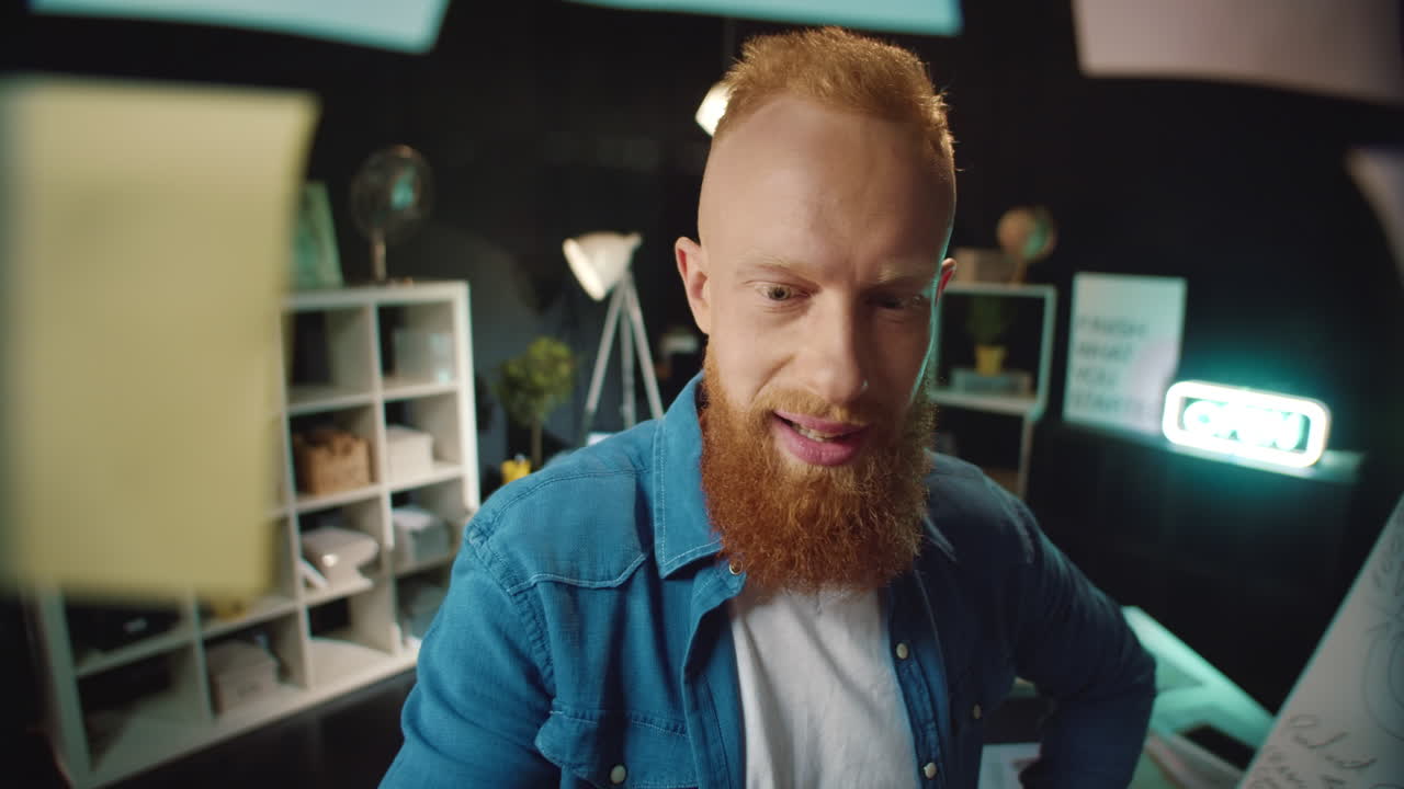 un hombre pelirrojo sonriente encontrando una pegatina con una buena solución en una oficina hipster.