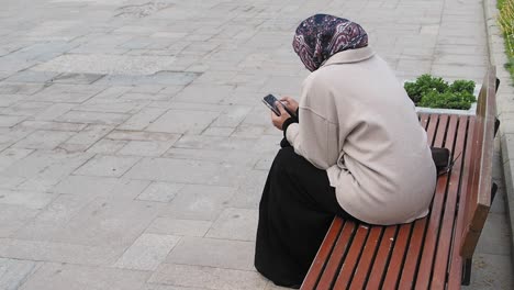 woman sitting on bench using phone