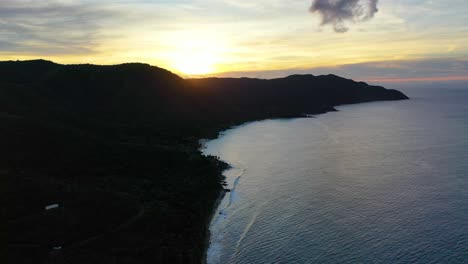 golden hour aerial view of the virgin islands shows a glowing sky of warm hues casting soft shadows on the calm caribbean waters and a tree-lined peninsula on st. croix