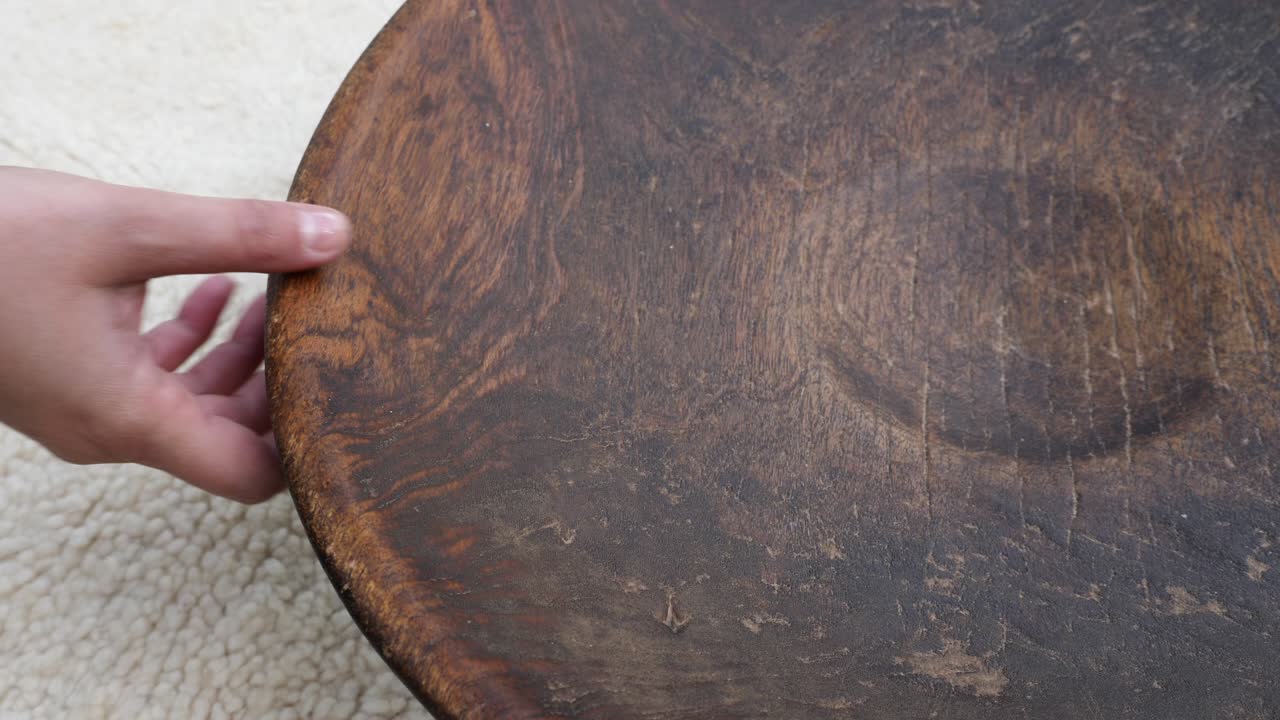 un cuenco de madera redondo antiguo en una alfombra tradicional bereber marroquí.