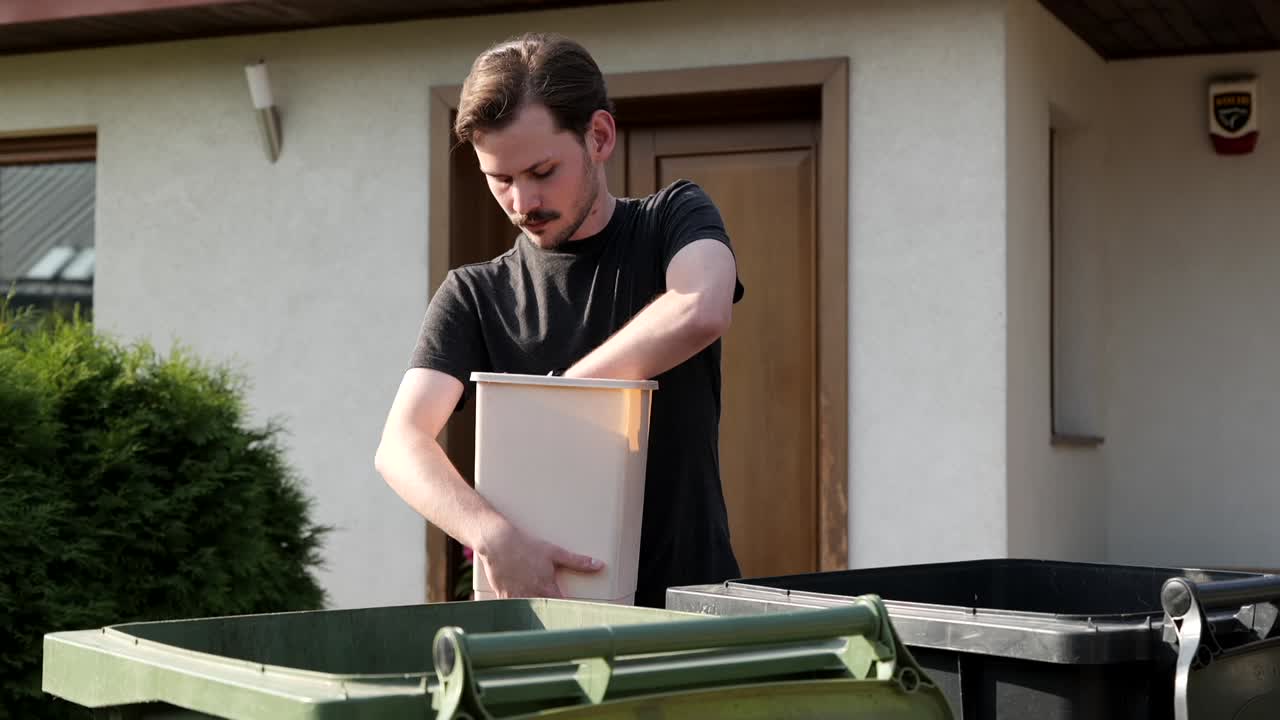 hombre caucásico sacando basura clasificando basura en contenedores para reciclar
