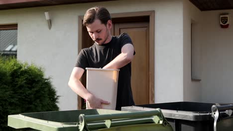 Caucasian-male-taking-out-trash-sorting-garbage-into-bins-for-recycling