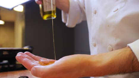 the chef pours olive oil on his hands