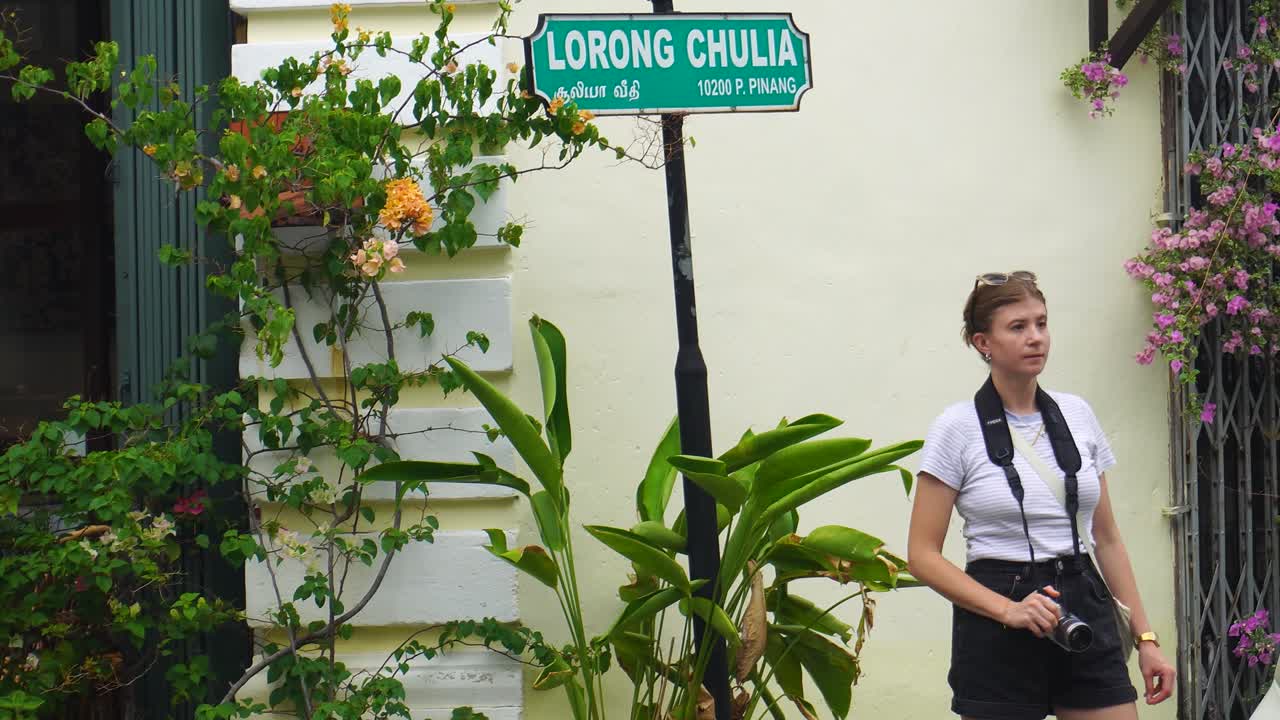 turista mujer tomando una foto al lado del letrero de lorong chulia en penang