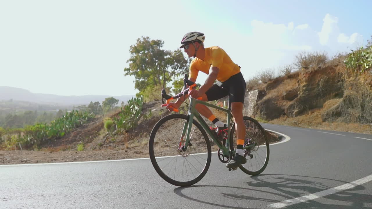 On an empty morning road, a man on a road bike participates in outdoor exercise. The slow-motion video emphasizes the concept of extreme sports