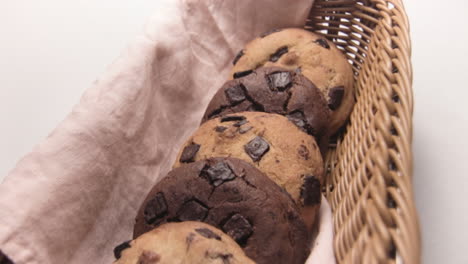 yummy chocolate chip cookies in wicker basket, white background