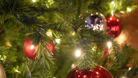 primer plano de un árbol de navidad al aire libre decorado festivamente con bolas rojas brillantes en un fondo de hadas brillantes borrosas. luces de guirnaldas desenfocadas, efecto bokeh. feliz navidad y feliz concepto de vacaciones.