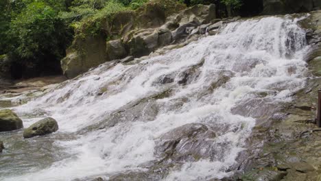 Water-gently-cascading-over-the-rocks-of-Goa-Rang-Reng-Waterfall-in-Bali,-captured-in-a-static-slow-motion-shot