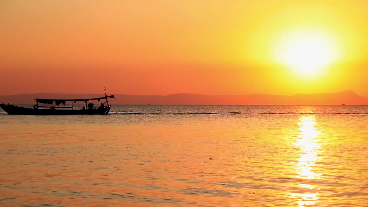 Dreamy summer scene of two traditional khmer long boat silhouette crossing paths on the sunset horizon in Koh Tonsay or Rabbit Island in Cambodia