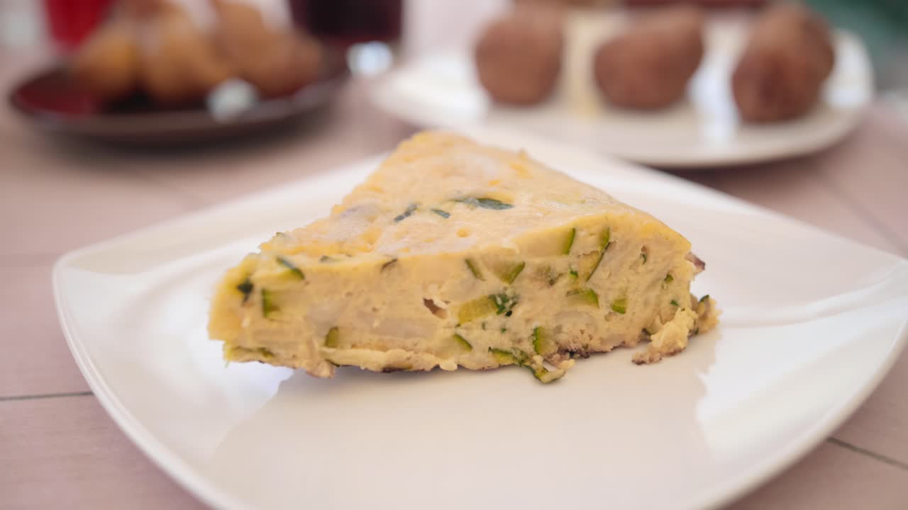 Close up view of an authentic spanish omelette 'Tortilla', made with eggs, fried potato and vegetables, sliced and served on a white plate.