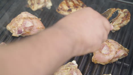 flipping chicken breasts on a barbecue revealing grill marks