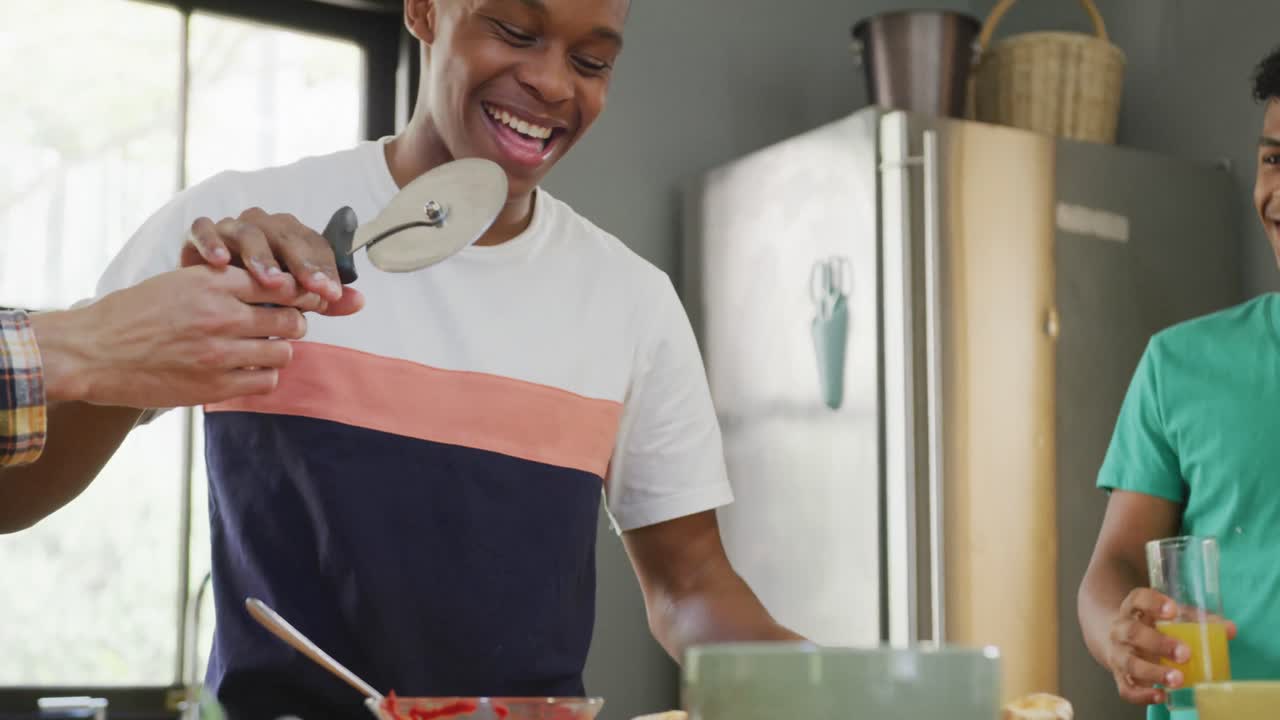 amigos adolescentes felices y diversos cortando pizza en la cocina, cámara lenta
