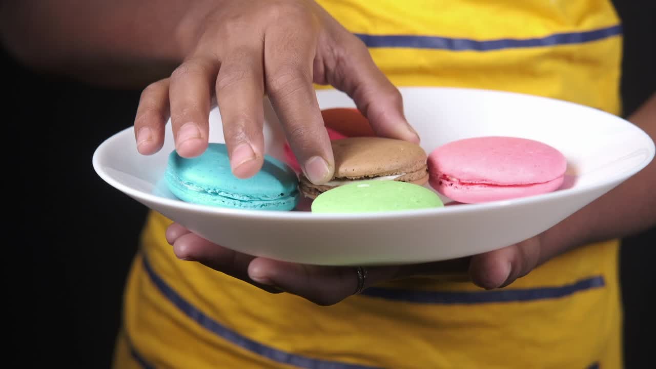 persona sosteniendo un plato de macarrones coloridos